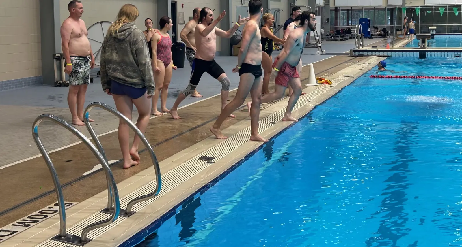 Club members running along the pool deck toward the water at the Shaw Centre in Saskatoon.